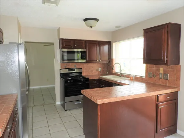 a kitchen with stainless steel appliances granite countertop a stove a sink and a refrigerator