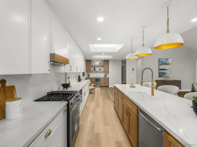 a large white kitchen with lots of counter space wooden floor and stainless steel appliances