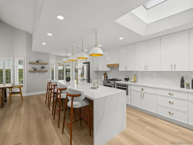 a dining room with kitchen island stainless steel appliances furniture a chandelier and living room view