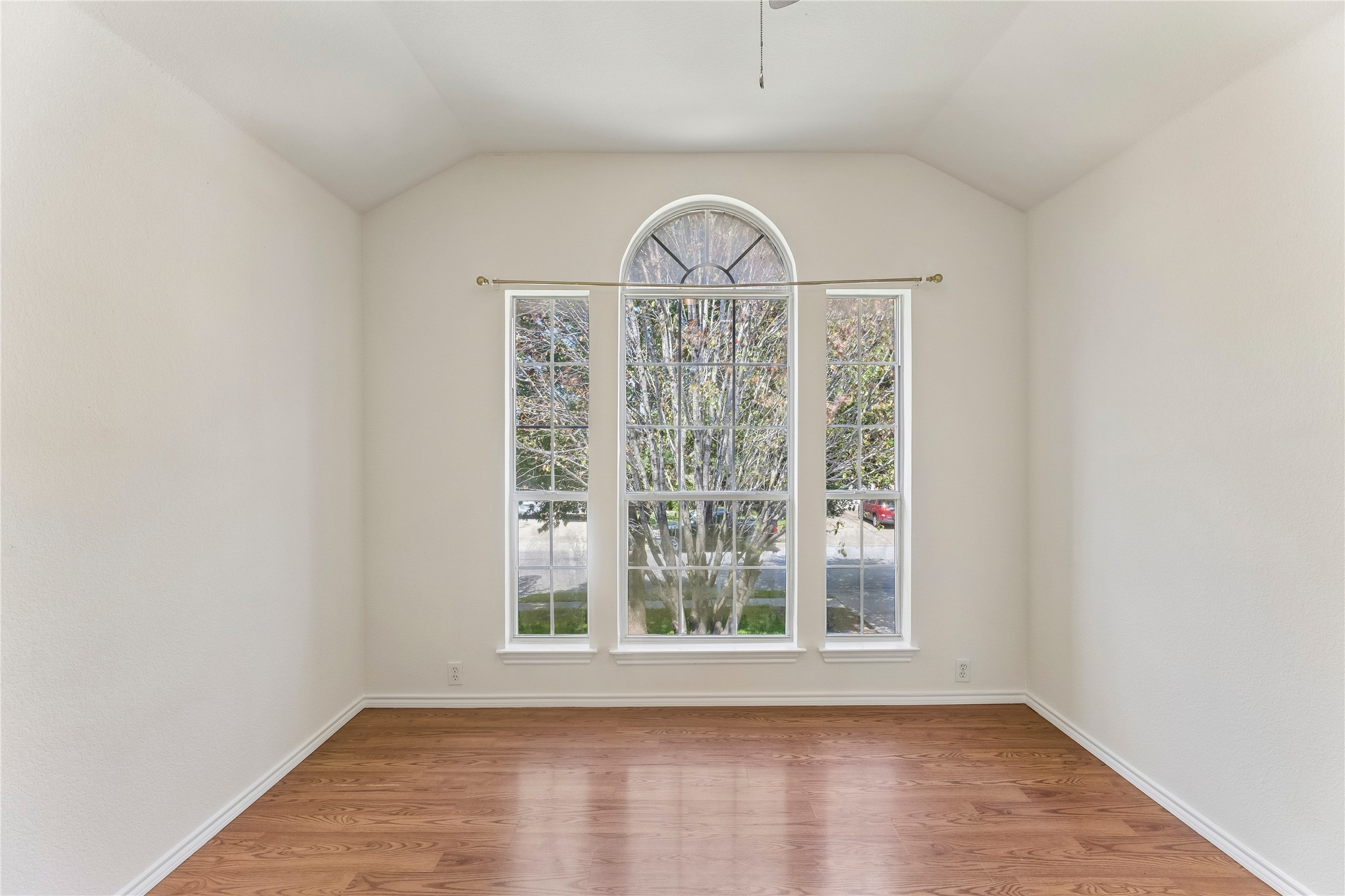 2372 Paradise Ridge Drive Round Rock, TX 78665 - Photo 29 of 40 Natural light streams into this versatile room through a large arched window with symmetrical side panels, highlighting the polished hardwood flooring.