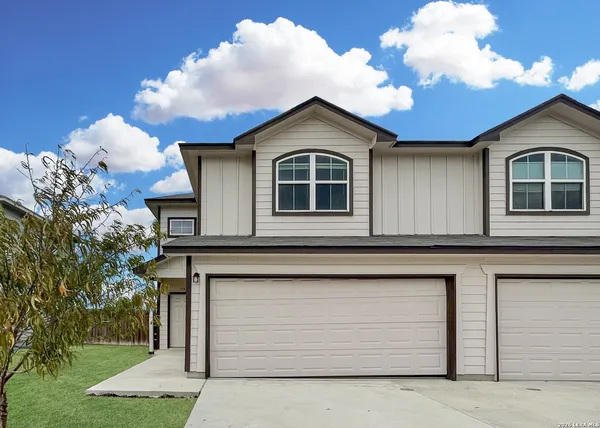 a view of a house with a small yard and a large tree