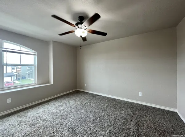 an empty room with windows and fan