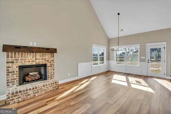 a view of an empty room with wooden floor fireplace and a window