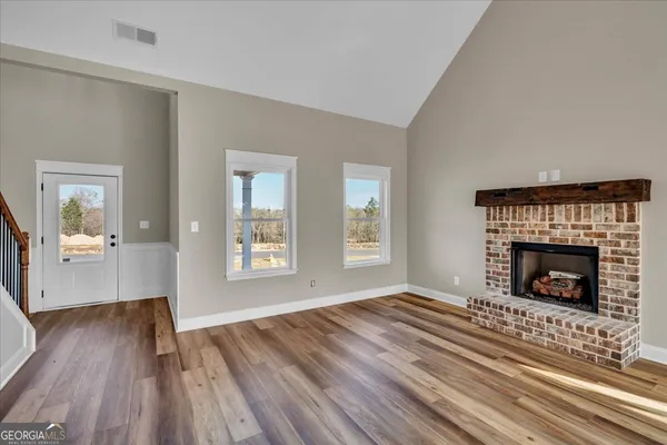 a view of an empty room with wooden floor fireplace and a window