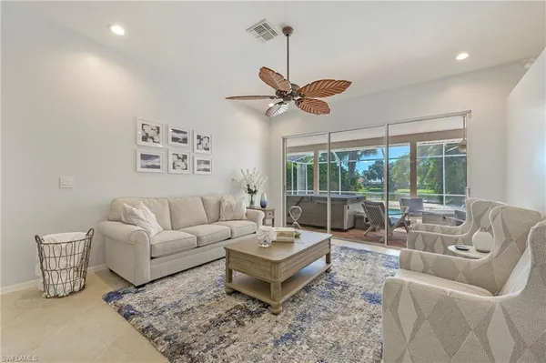a living room with furniture a ceiling fan and a large window