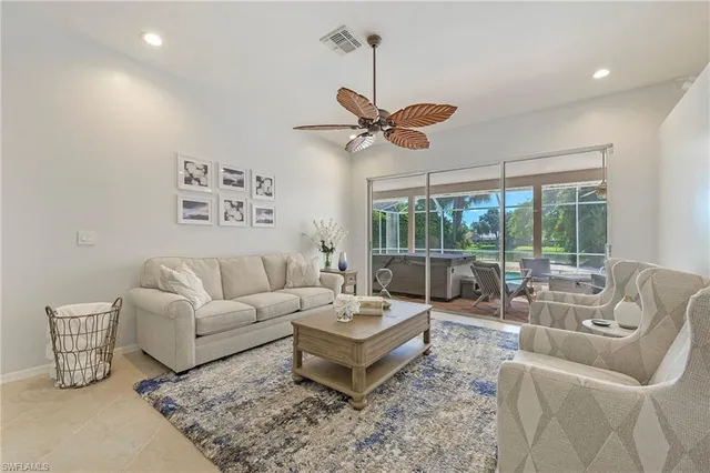 a living room with furniture a ceiling fan and a large window