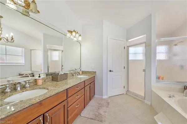 a spacious bathroom with a granite countertop double vanity sink a mirror and a bathtub