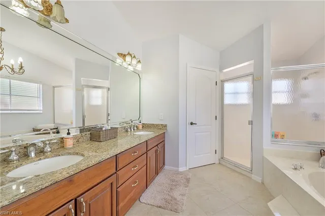 a spacious bathroom with a granite countertop double vanity sink a mirror and a bathtub