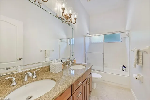 a bathroom with double vanity sinks a toilet a mirror and shower