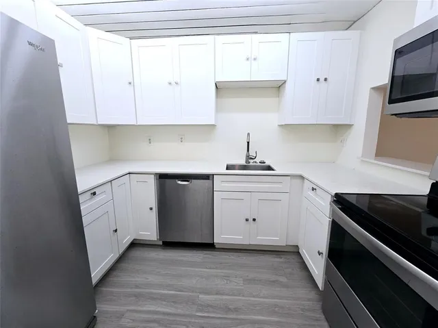 a kitchen with white cabinets stainless steel appliances and sink