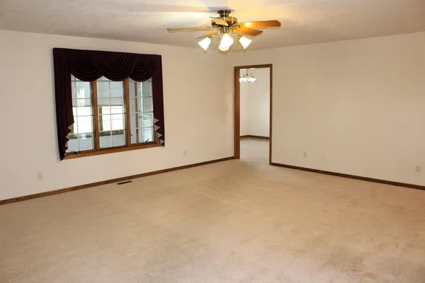an empty room with windows and fan