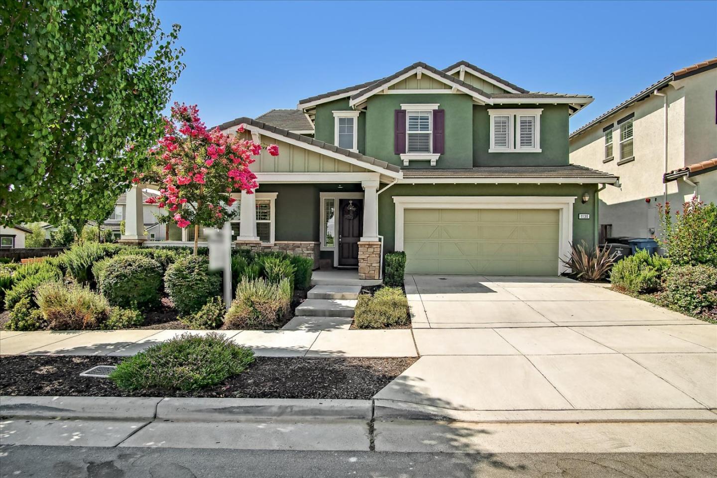 a front view of a house with garage and plants