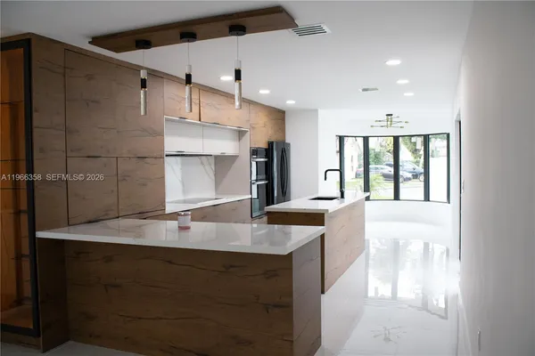 a large kitchen with kitchen island a large counter top space a sink stainless steel appliances and cabinets