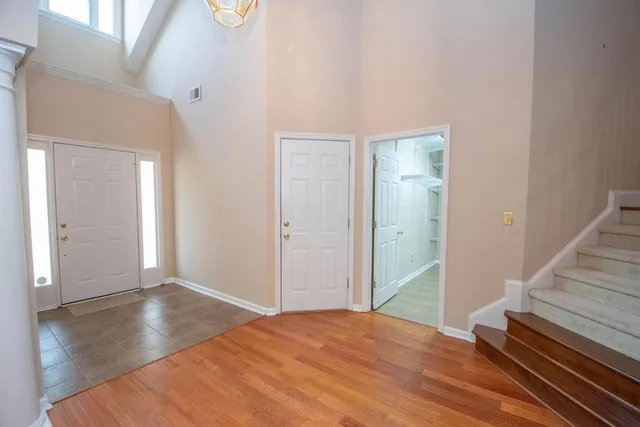 a view of an empty room with wooden floor and stairs