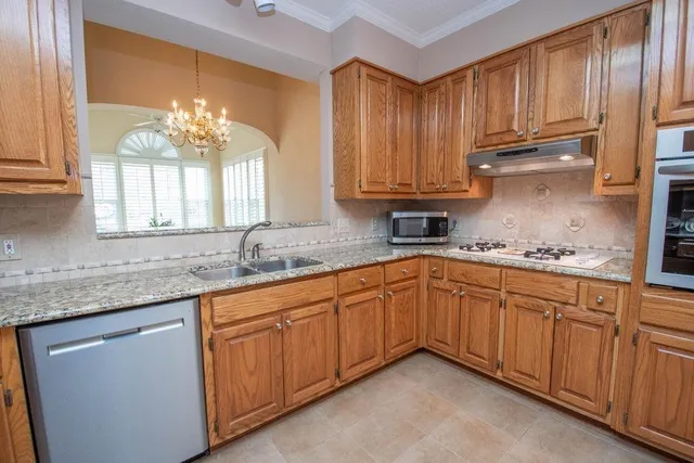 a kitchen with granite countertop a sink stainless steel appliances wooden cabinets and a counter top space