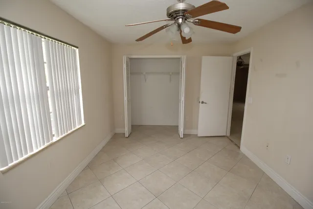 an empty room with windows and fan