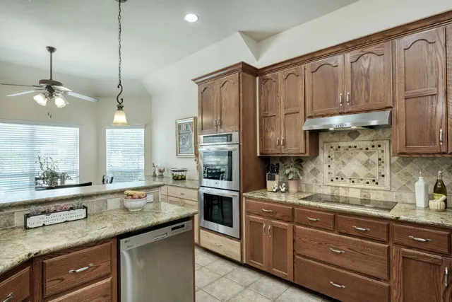 a kitchen with stainless steel appliances granite countertop a refrigerator a sink and a stove