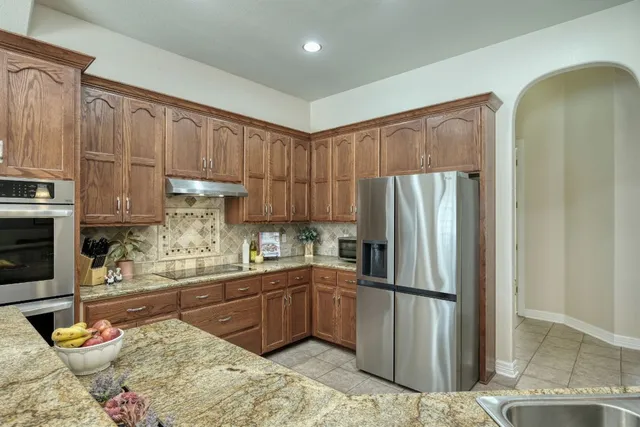 a kitchen with stainless steel appliances granite countertop a sink a stove and cabinets