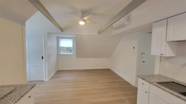 a view of an empty room with wooden floor and cabinets