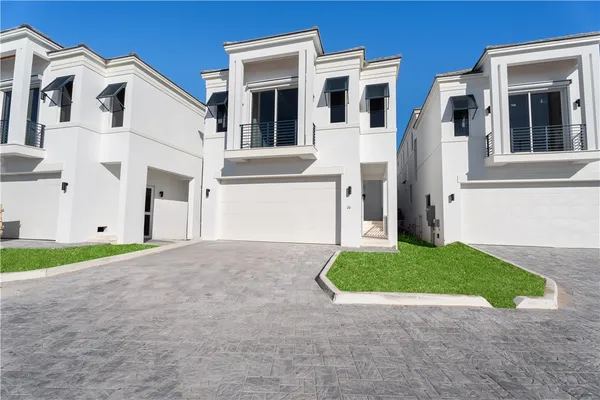 a view of a white house with a yard and garage