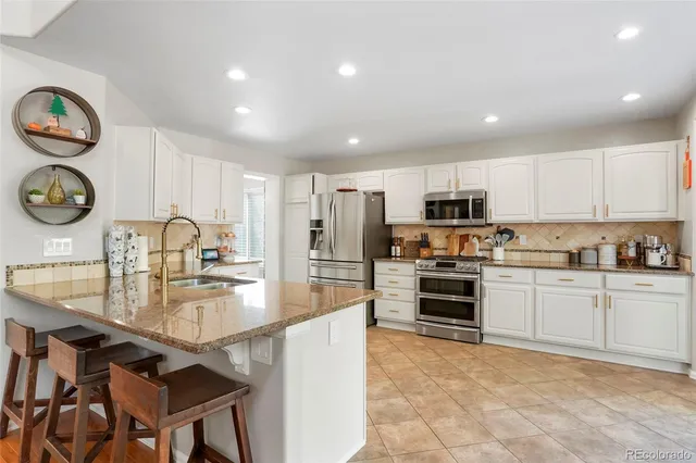 a large kitchen with kitchen island granite countertop a stove top oven a sink a counter space and cabinets