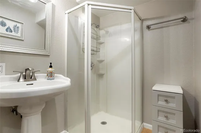 a bathroom with a sink a mirror a glass door and shower