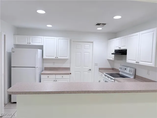 a kitchen with stainless steel appliances granite countertop a refrigerator a stove a sink a microwave and white cabinets with wooden floor