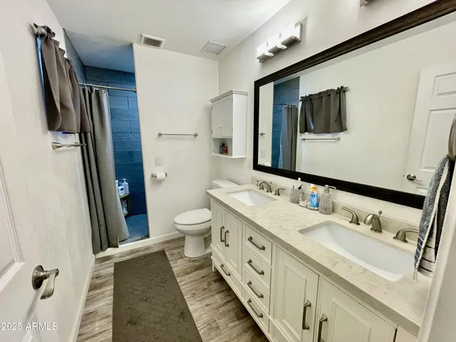 a bathroom with a double vanity sink toilet and mirror