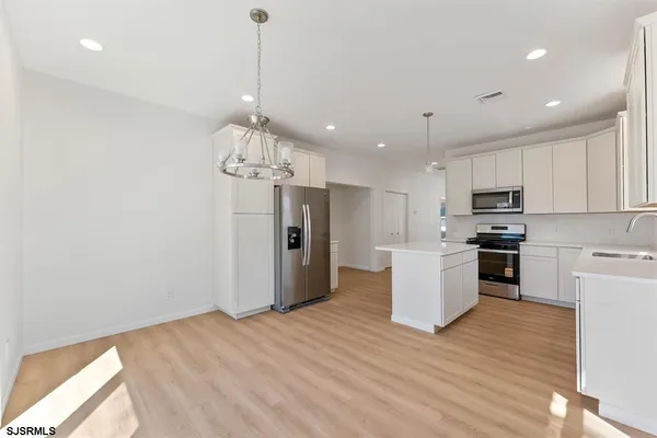 a kitchen with stainless steel appliances granite countertop a refrigerator a stove top oven a sink dishwasher and a refrigerator with wooden floor