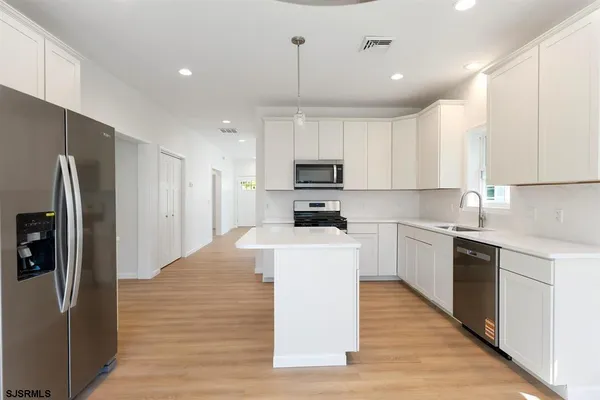 a kitchen with kitchen island white cabinets and stainless steel appliances