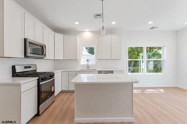 a kitchen with stainless steel appliances granite countertop a sink a stove top oven a counter space and cabinets