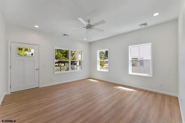 a view of an empty room with a window and wooden floor