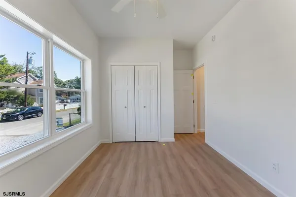 a view of hallway with window and wooden floor