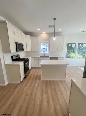 a large kitchen with stainless steel appliances a large counter top a stove a sink dishwasher and a refrigerator