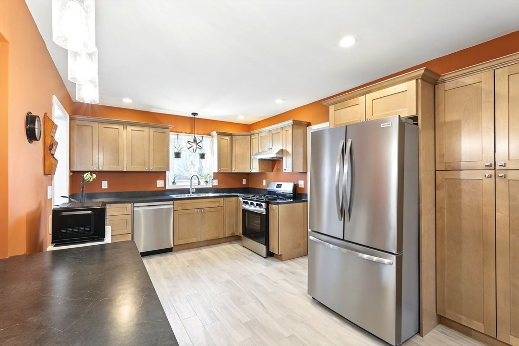 a kitchen with granite countertop stainless steel appliances a refrigerator a stove top oven and sink