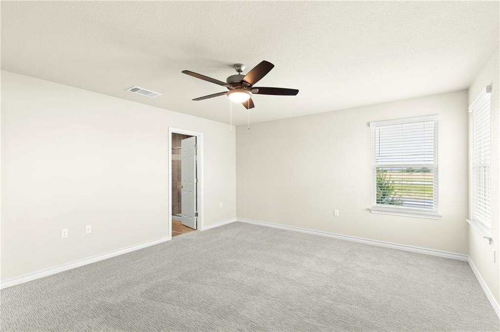 1624 Caballo Blanco Road Austin, TX 78725 - Photo 13 of 23 A well-lit bedroom provides comfortable living space with a ceiling fan and soft carpeting.