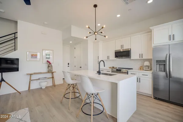 a kitchen with stainless steel appliances a stove a sink dishwasher a refrigerator and white cabinets with wooden floor