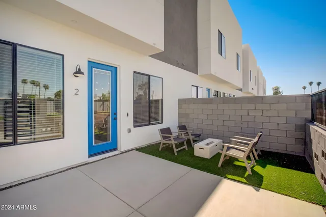 a patio with table and chairs and potted plants