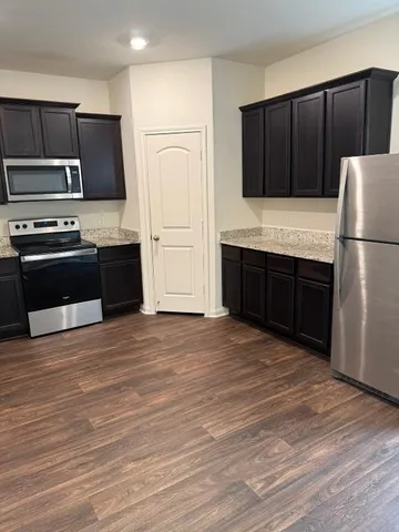 a kitchen with granite countertop a refrigerator and a stove top oven