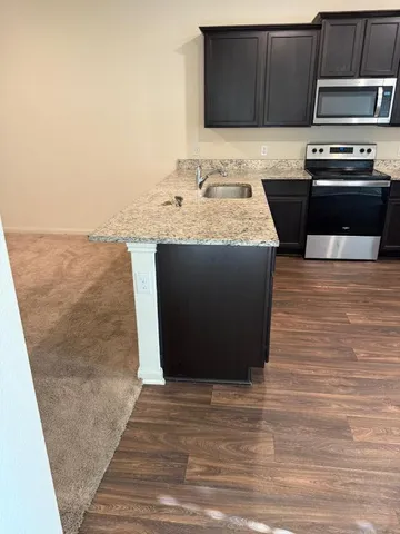 a kitchen with stainless steel appliances granite countertop a stove a sink and a microwave