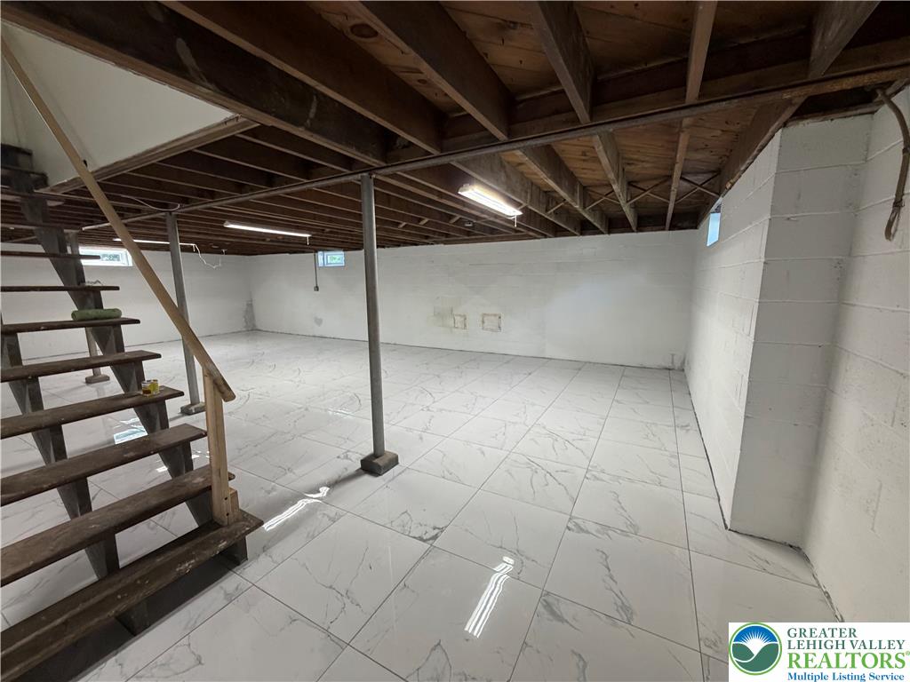 848 Hausman Road Allentown, PA 18104 - Photo 6 of 11 Ready for transformation, this spacious unfinished basement features a clean, tiled floor and structural wood beams.