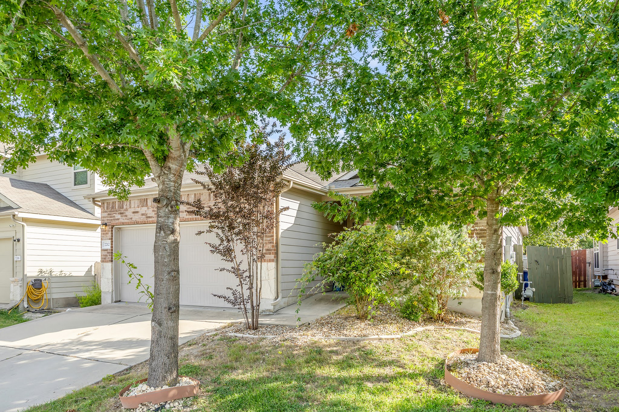 7212 Vail Ridge Street Austin, TX 78744 - Photo 23 of 26 Mature trees and lush landscaping frame this inviting suburban home.