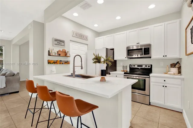 a kitchen with stainless steel appliances a stove a sink a microwave a refrigerator and cabinets