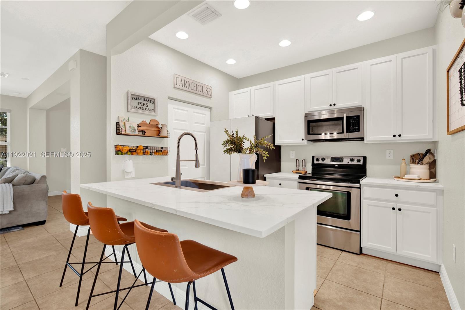 1121 Southwest 147th Terrace Pembroke Pines, FL 33027 - Photo 11 of 32 a kitchen with stainless steel appliances a stove a sink a microwave a refrigerator and cabinets