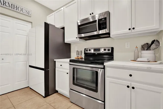 a kitchen with stainless steel appliances granite countertop white cabinets a stove a microwave and a refrigerator