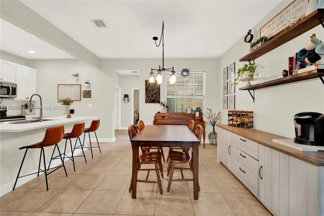 a kitchen with stainless steel appliances kitchen island granite countertop a dining table chairs and sink