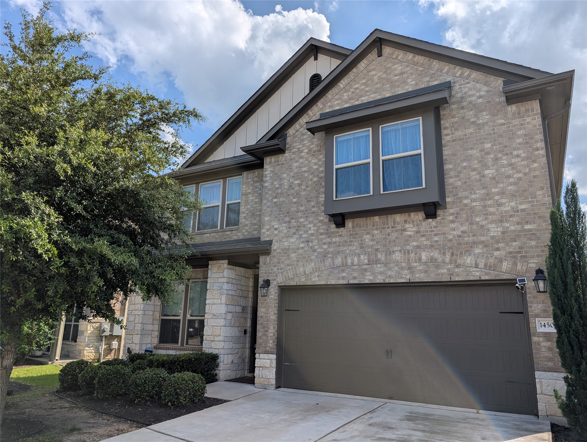 14502 McCoy Loop Austin, TX 78717 - Photo 3 of 26 Brick and stone exterior featuring a two-car garage, prominent front windows with decorative trim, and a covered entry