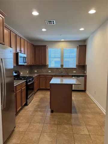 a kitchen with stainless steel appliances granite countertop a stove a sink and a refrigerator