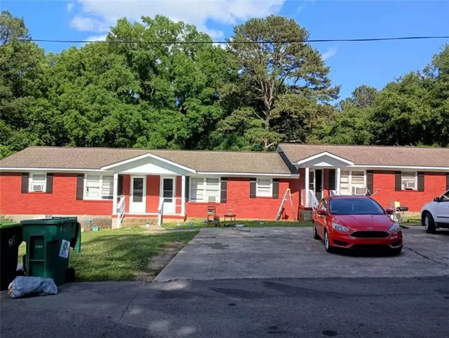 a front view of a house with a garden and trees