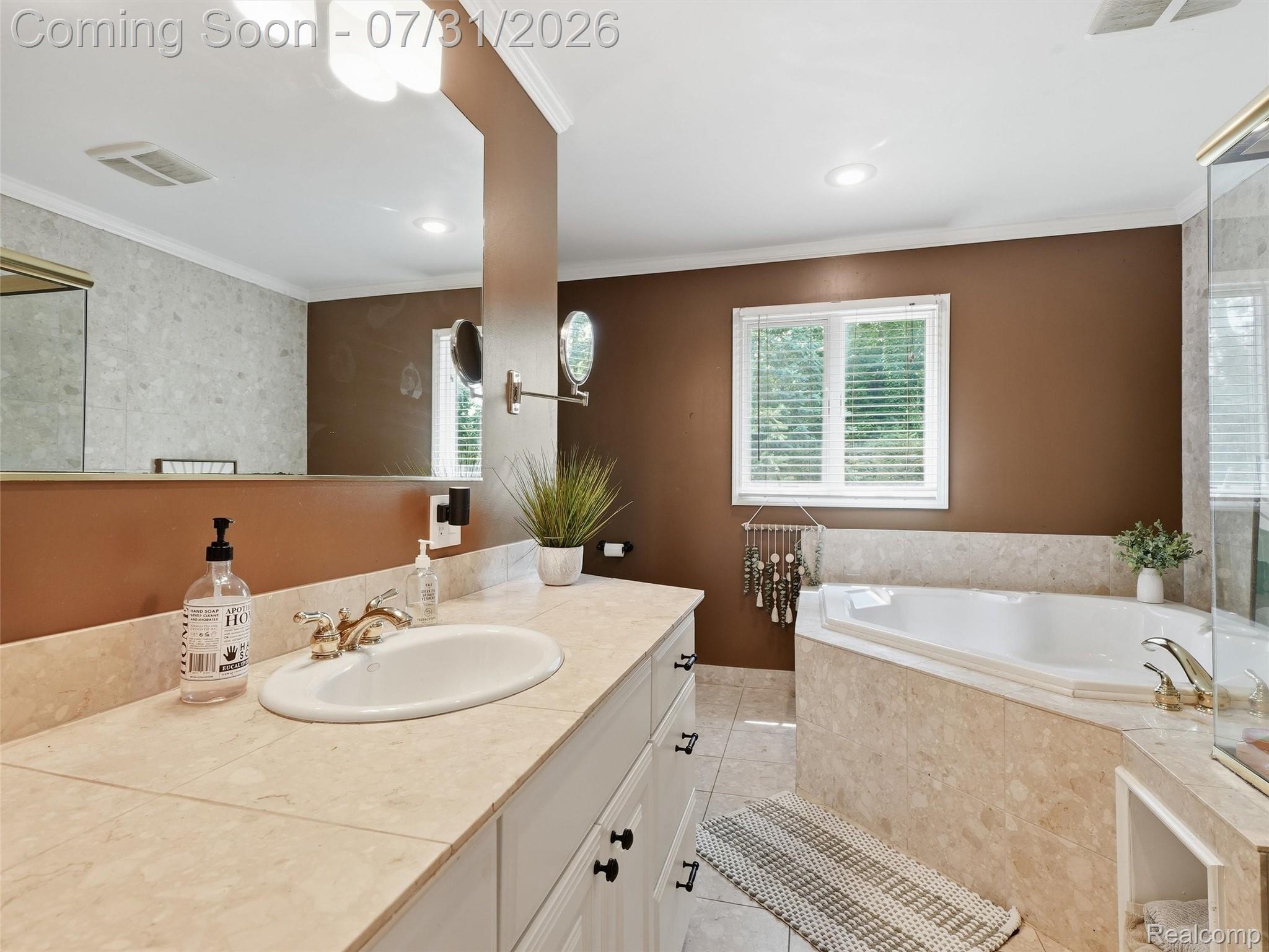 138 Aintree Road Rochester, MI 48306 - Photo 30 of 53 Bathroom featuring a built-in corner soaking tub, vanity with an integrated sink, tiled countertop, and a large wall mirror